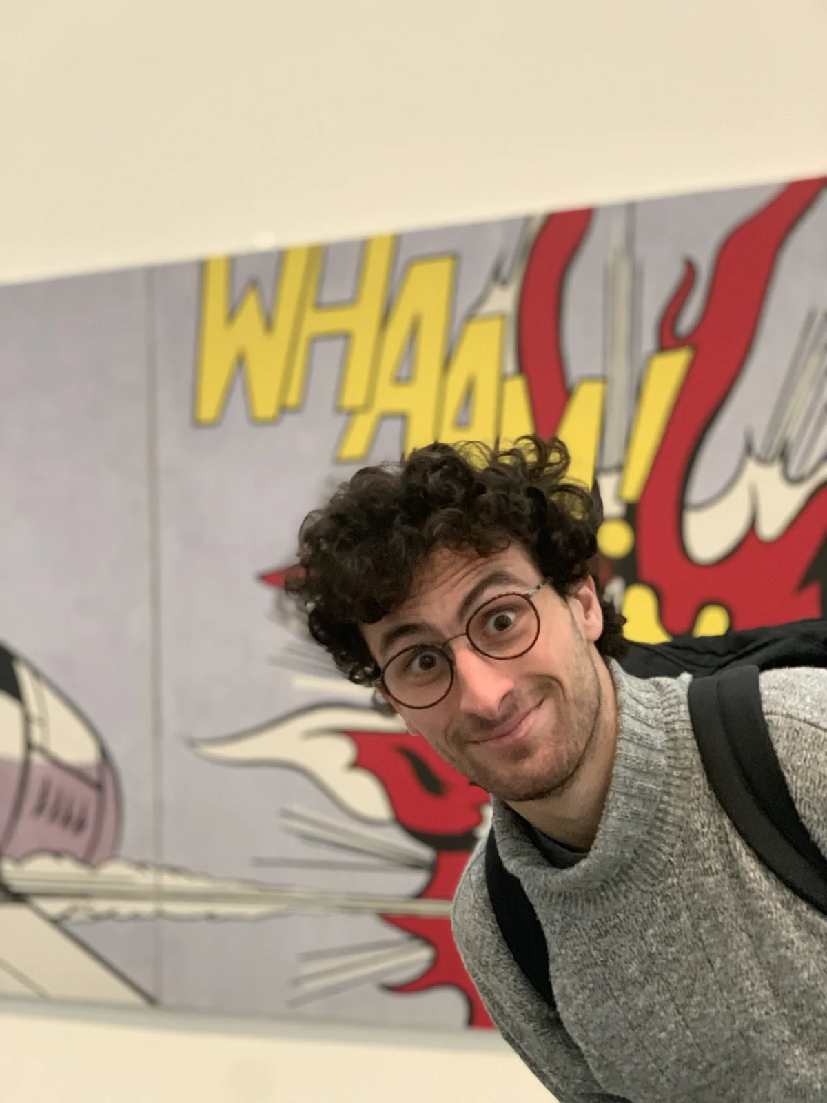 Andrea wearing glasses in front of a colourful artwork
